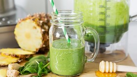 Świeżo przyrządzone zielone warzywne smoothie w szklanym słoiku ze słomką
