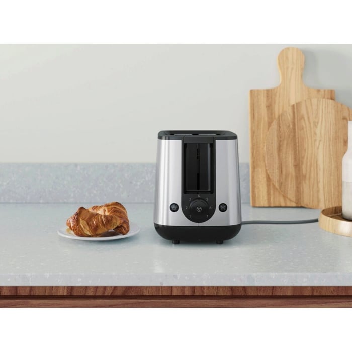 A silver toster with bread toasts on a table