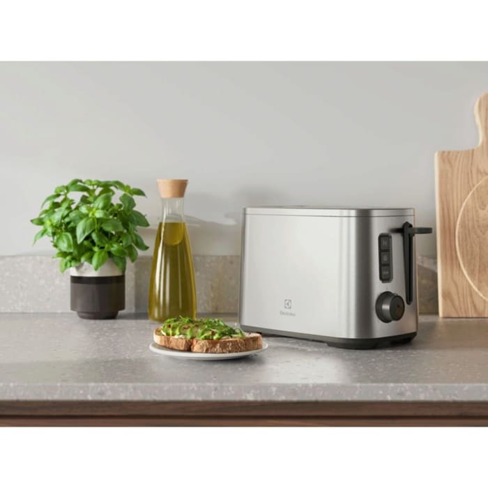 A silver toaster with toast sandwiches on a plate