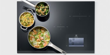 Trzy naczynia na powierzchni grzejnej FreeZone płyty indukcyjnej Electrolux Infinite Combi