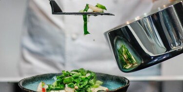 Szef kuchni nakładający na talerz potrawę z rondla Infinite Chef