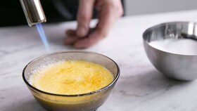 Cukiernik karmelizujący cukier na wierzchu deseru creme brulee za pomocą ręcznego palnika gazowego