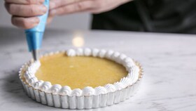 Cukiernik nakładający gładką masę bezową na tartę cytrynową