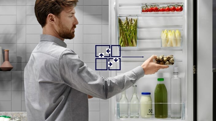 Mężczyzna porządkujący produkty w drzwiach chłodziarki