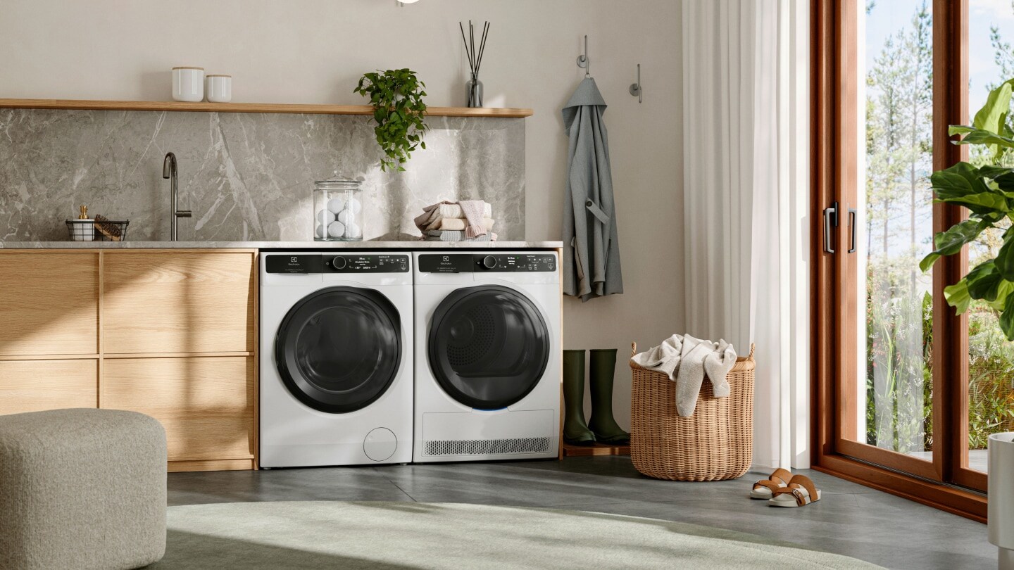 Pralnia z pralką i suszarką bębnową Electrolux stojącymi obok siebie pod blatem.