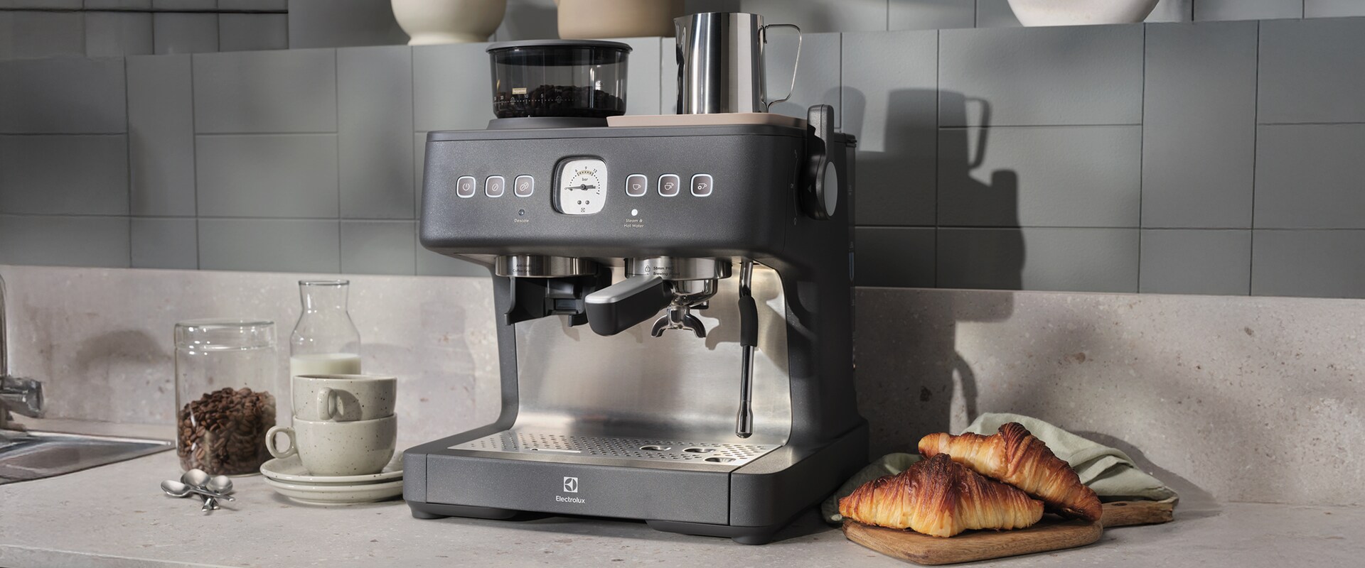 Zdjęcie ekspresu do kawy Electrolux na kuchennym blacie obok świeżych croissantów