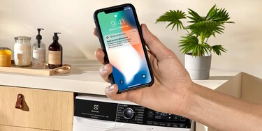 kobieta patrząca na ekran aplikacji My Electrolux w telefonie komórkowym